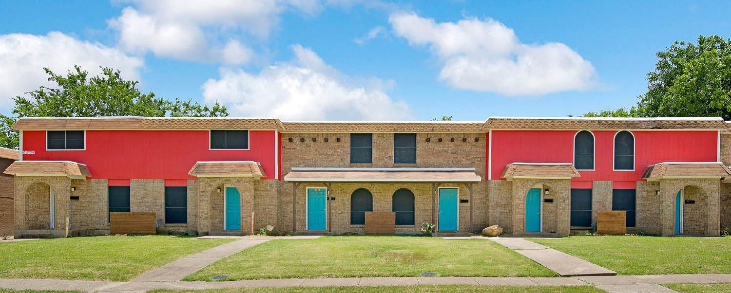 Two story brick townhomes with teal doors and arched entries under a blue sky