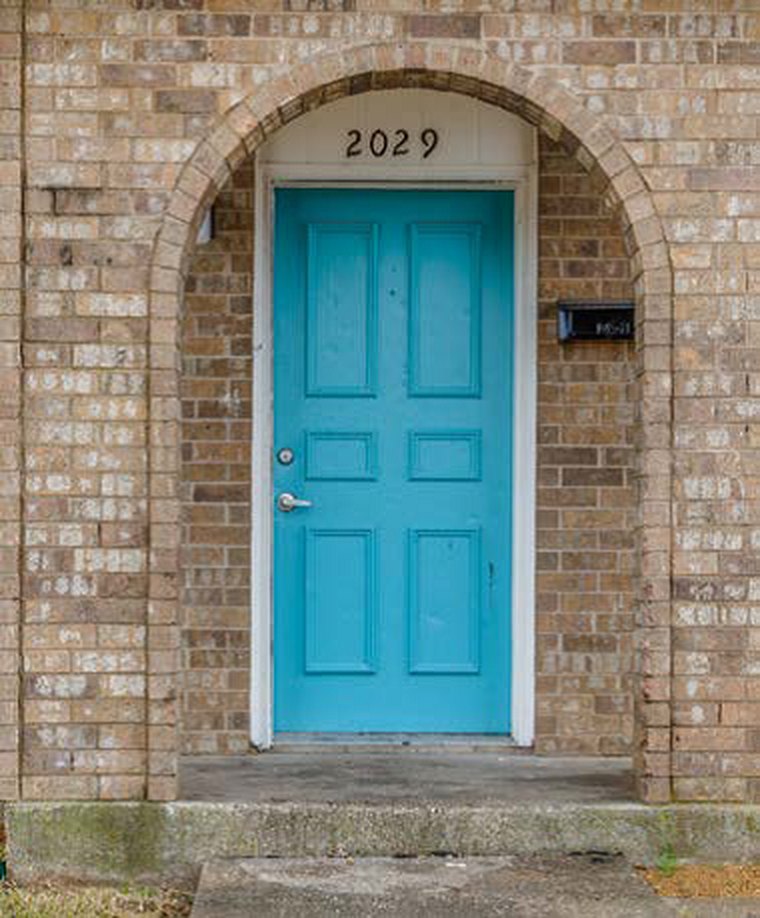Teal front door in a brick archway